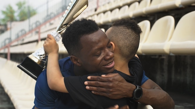 Dad hugging and supporting his son after a competition.