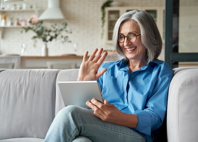 Older woman on a zoom call waving to the screen.