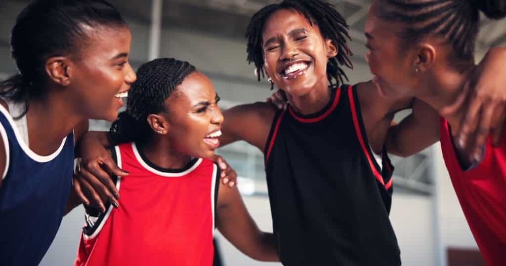 Basketball teammates laughing and supporting each other in a team huddle.  