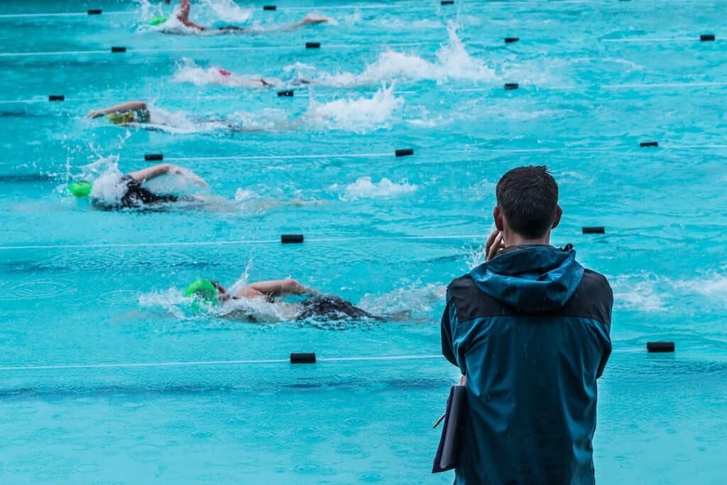 Swim coach watching swim meet from the side of the pool.