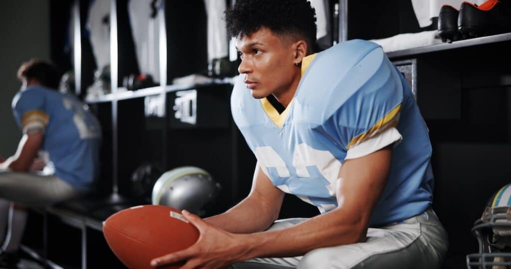 Young man in locker room in deep thought, meditating before a game.