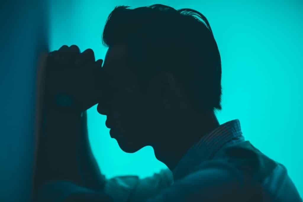 Anxious young man leaning against a wall.