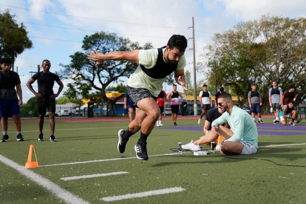 Male sprinter accelerating while coach watches him and times him.