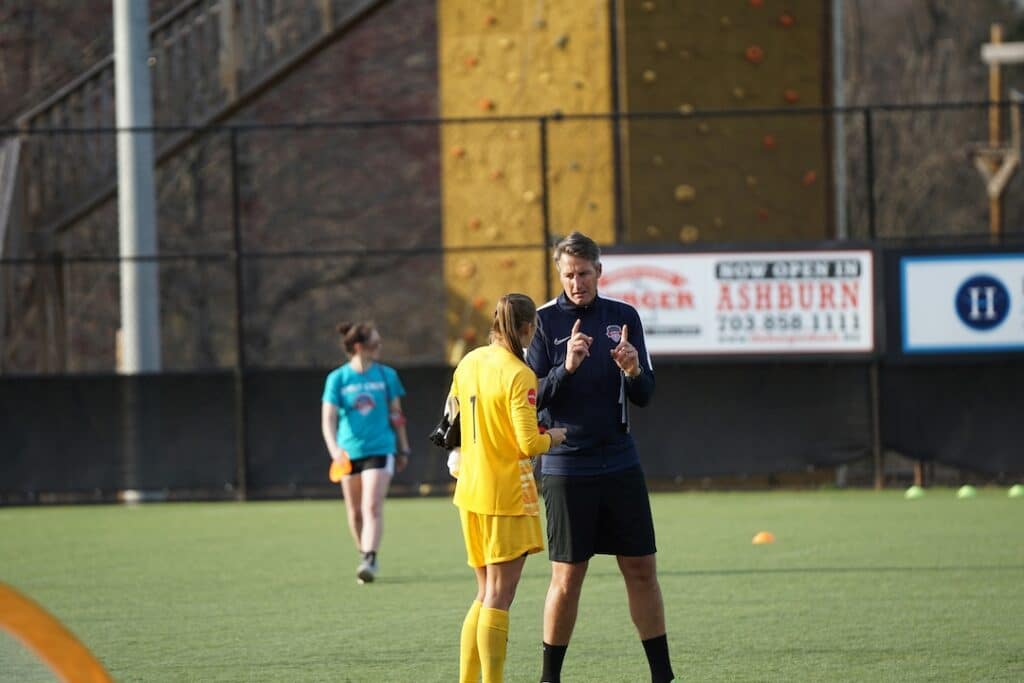 Soccer coach talking to his player on the field.