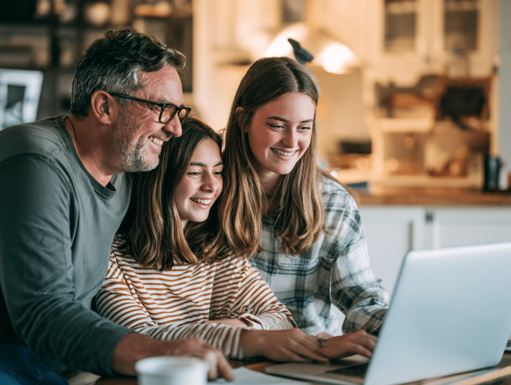 A father working with his two daughters on a laptop.