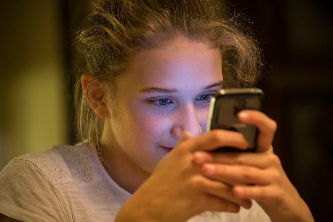 Teenager up close using her phone and grinning